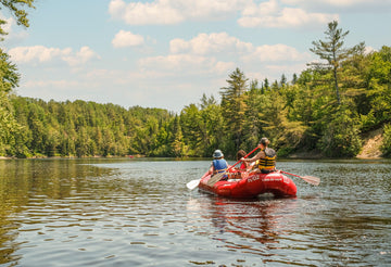 A raft heading downriver between forested banks