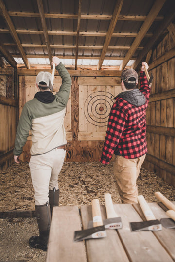 Two guests throwing axes at targets in the covered range