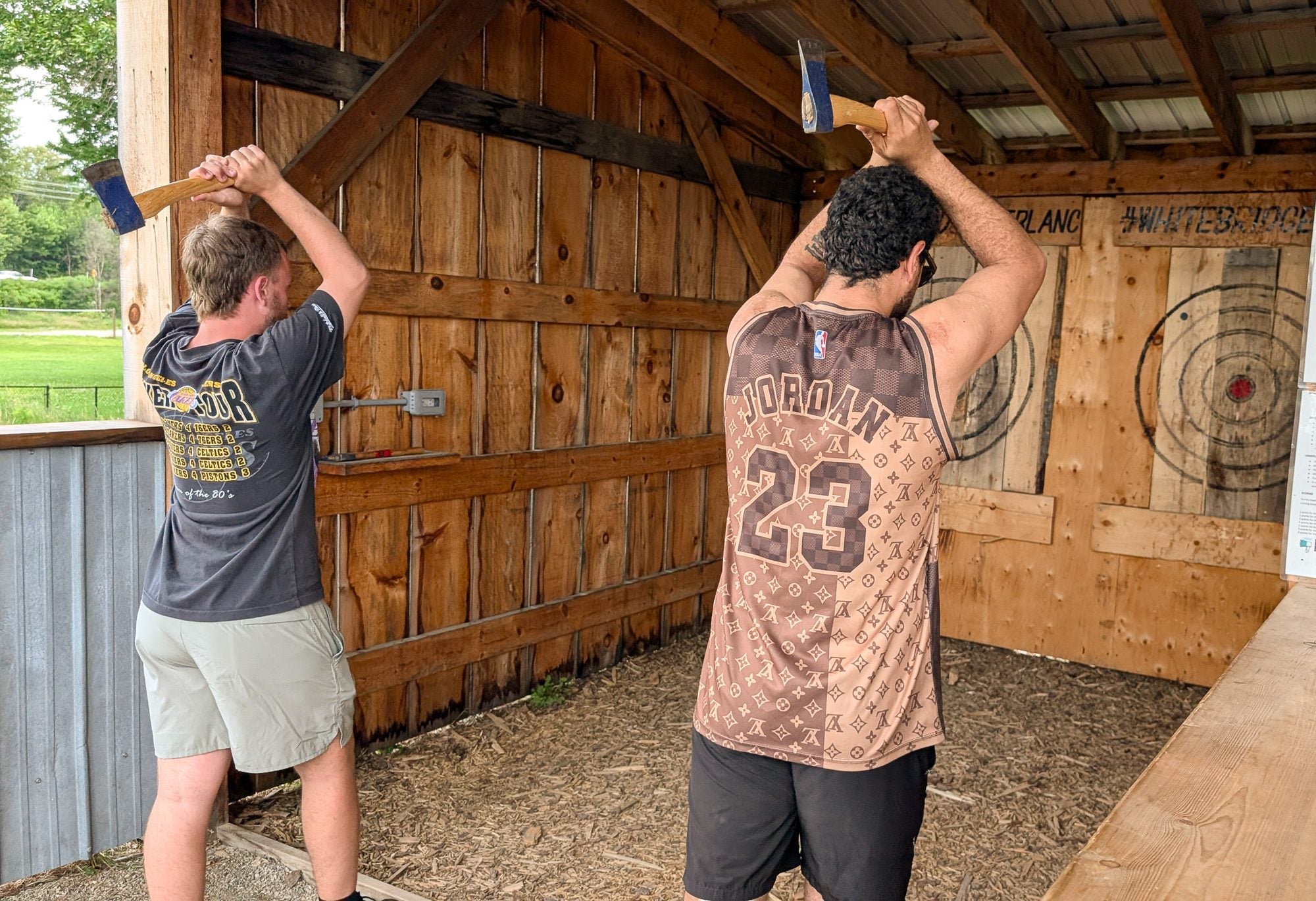 Two guests throwing axes in the covered rangesl2